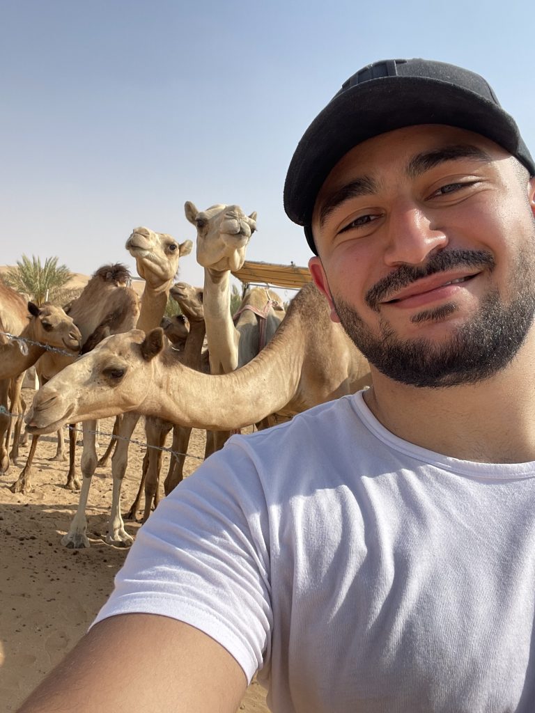 Bassam Tabibi mit einer Kamelenherde im Hintergrund